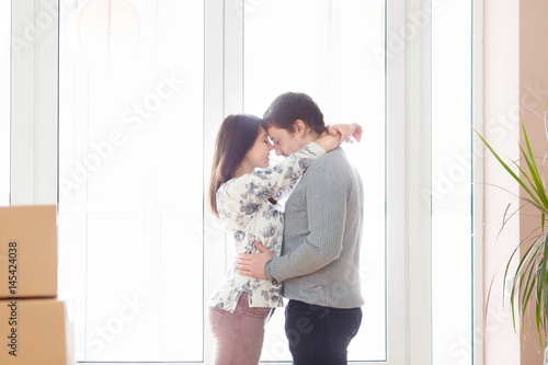 Happy young couple moving into new apartment with packaging boxes