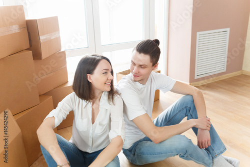 Happy young couple moving into new apartment with packaging boxes
