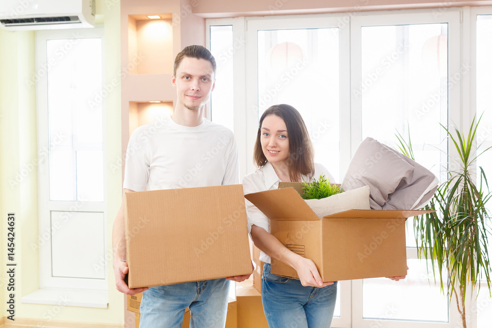 Happy young couple moving into new apartment with packaging boxes Happy young couple moving into new apartment with packaging boxes