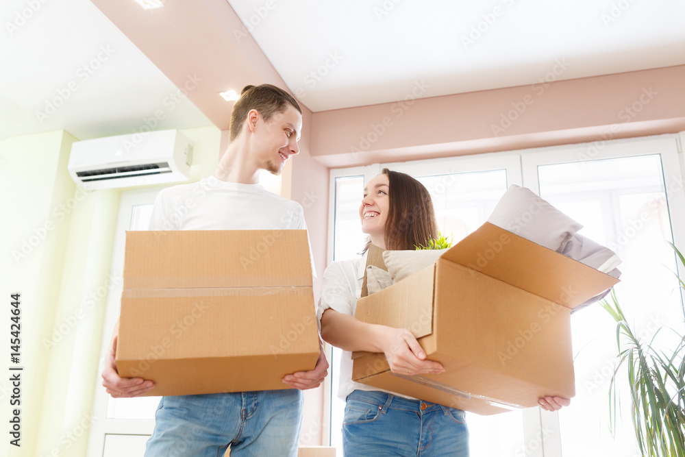 Happy young couple moving into new apartment with packaging boxes Happy young couple moving into new apartment with packaging boxes