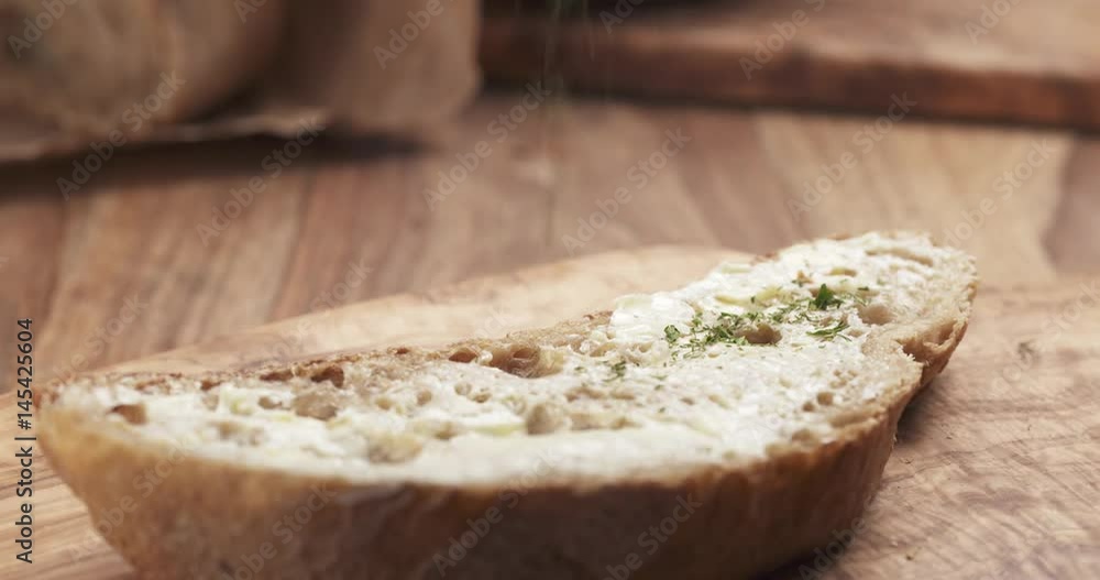 Slow motion of herbs falling on rustic bread with butter, 4k 60fps prores footage Slow motion of herbs falling on rustic bread with butter, 4k 60fps prores footage
