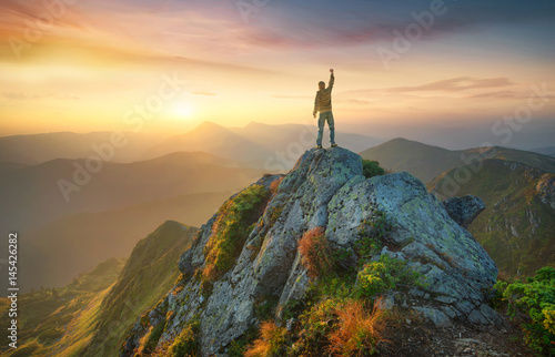 Obraz na plátně Tourist on the peak of high rocks. Sport and active life concept