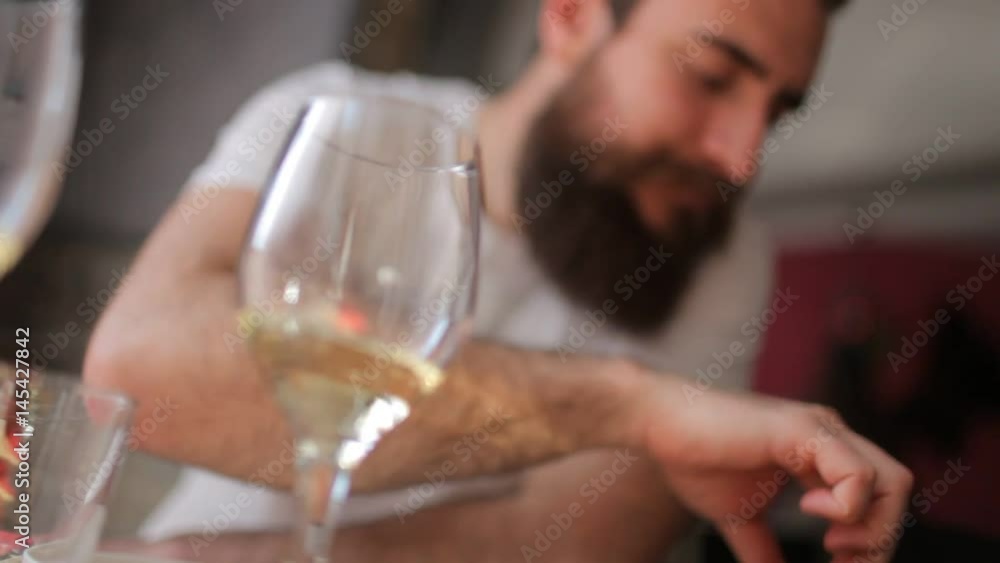 Young man with a beard drinking a glass of white wine Young man with a beard drinking a glass of white wine
