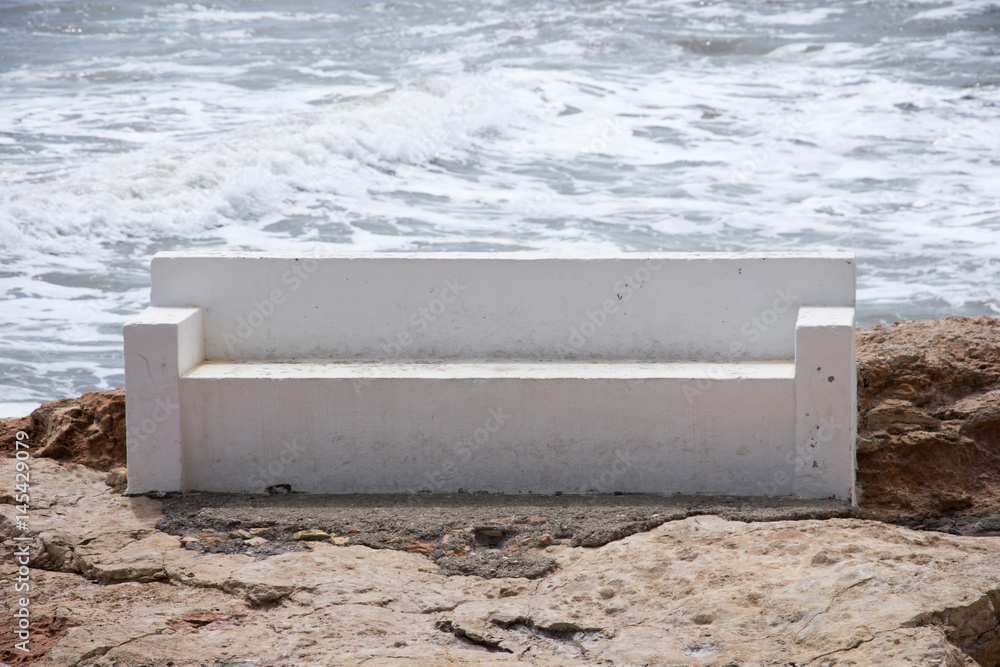 White bench of stone on the beach in the afternoon during a storm White bench of stone on the beach in the afternoon during a storm