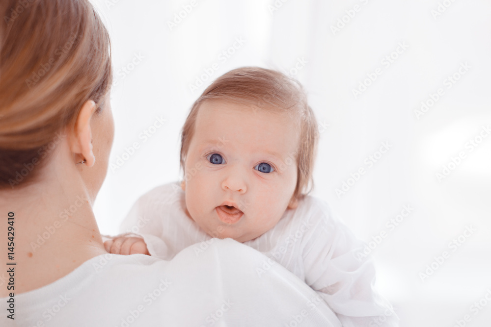 Young mother and newborn baby in white bedroom Young mother and newborn baby in white bedroom