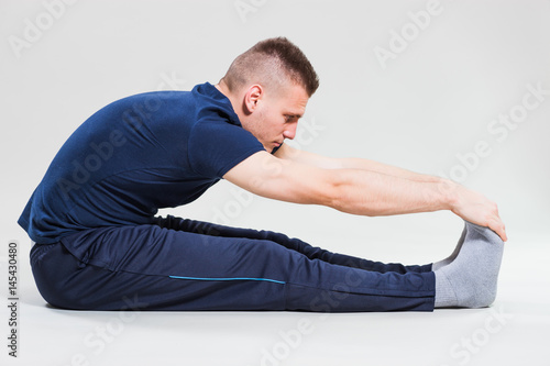 Studio shot image of young man who is stretching his body. 