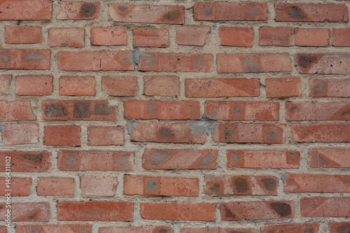 The texture of the background. An old wall of red cracked brick and cement with uneven masonry.