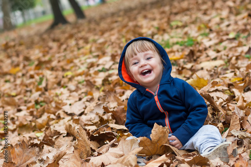 Happy little child, baby boy laughing and playing in autumn