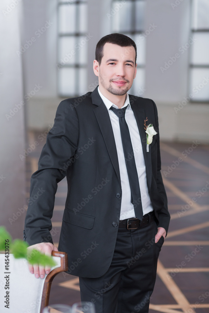 Handsome elegant groom in black wedding tuxedo with white shirt