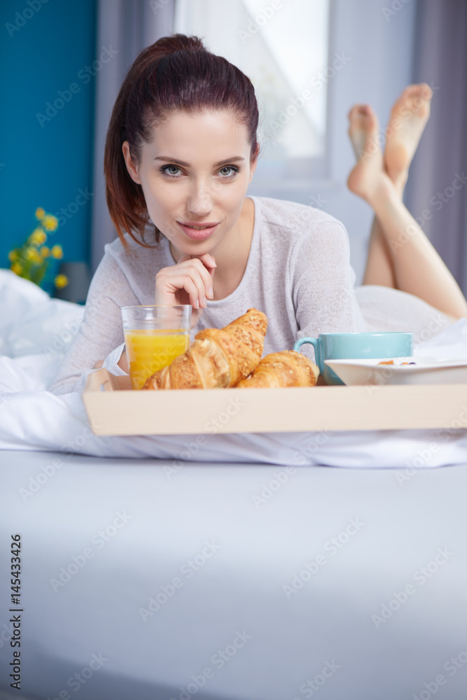 young beauty  woman having breakfast in bed early sunny morning