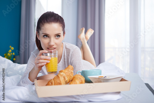 young beauty woman having breakfast in bed early sunny morning