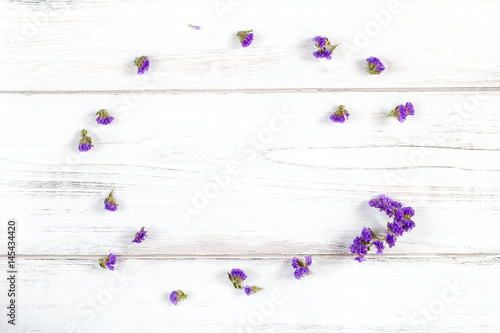 Violet flowers frame composition on a rustic white wooden background,
