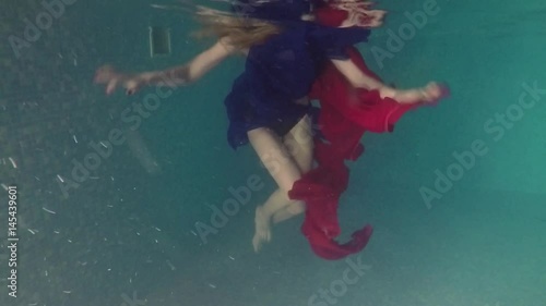 Slim body of a girl in blue and red matter. Underwater shooting photo