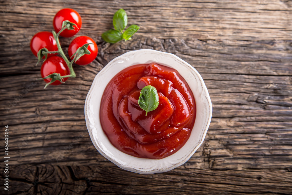 Ketchup or tomato sauce in white bowl and cherry tomatoes on wooden table. Ketchup or tomato sauce in white bowl and cherry tomatoes on wooden table.