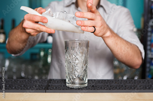 Barman's hands pouring ice for cocktail