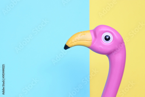 Pink plastic flamingo on pastel background with room for copy.