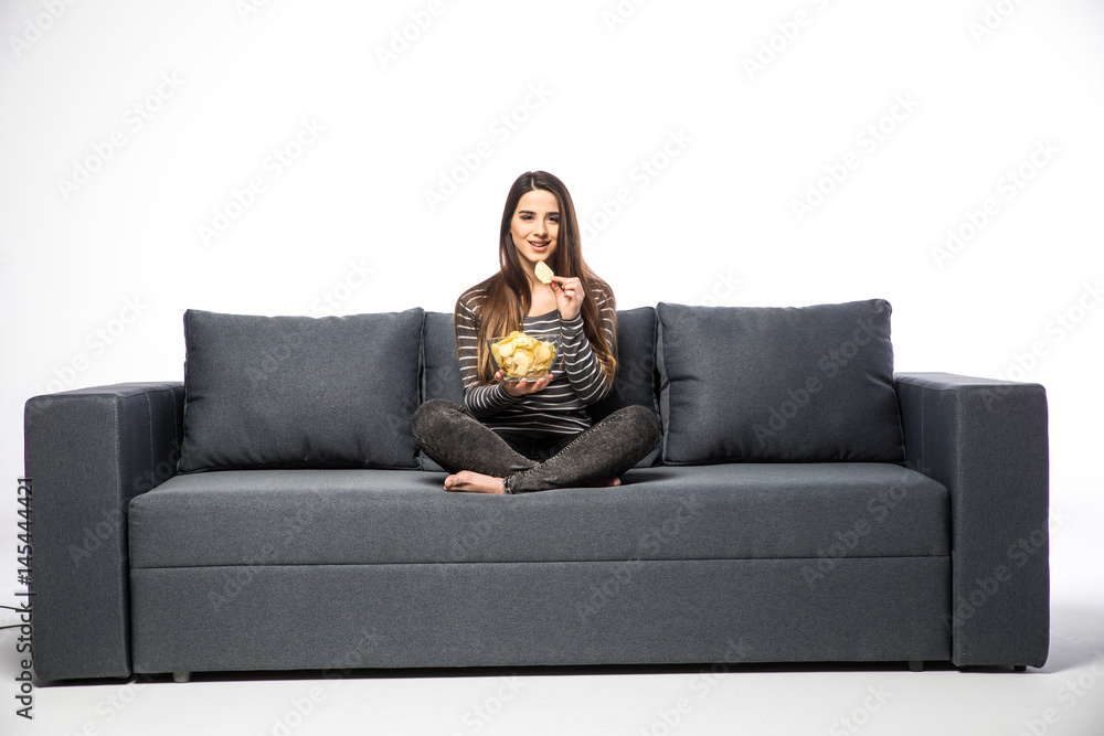 Young woman watching TV and eating chips sitting on sofa Young woman watching TV and eating chips sitting on sofa