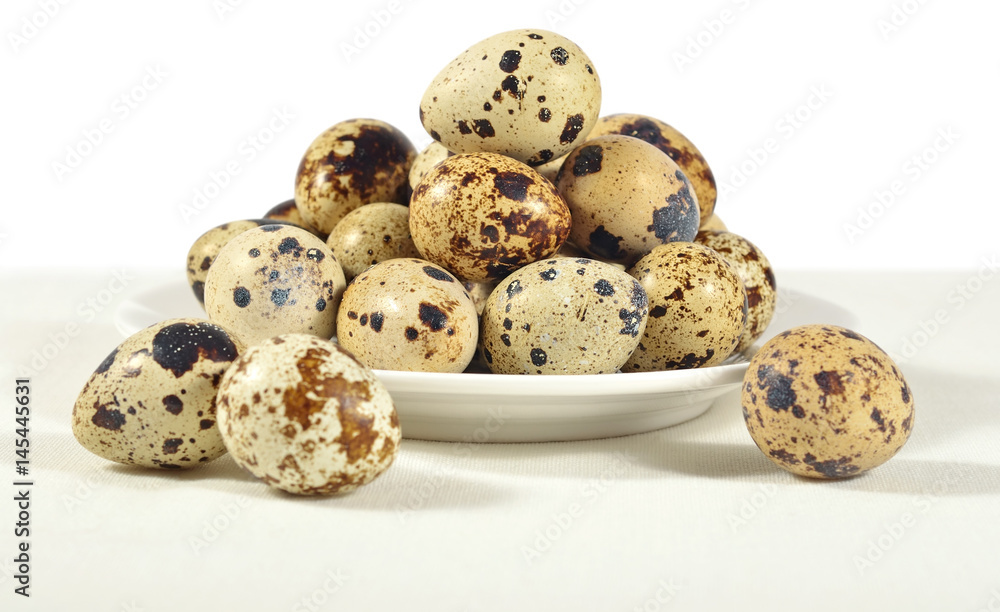 Quail eggs in a white bowl on a white