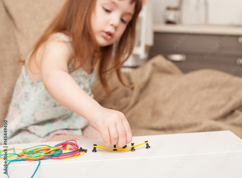 Girl builds shapes from colored rubber bands Girl builds shapes from colored rubber bands