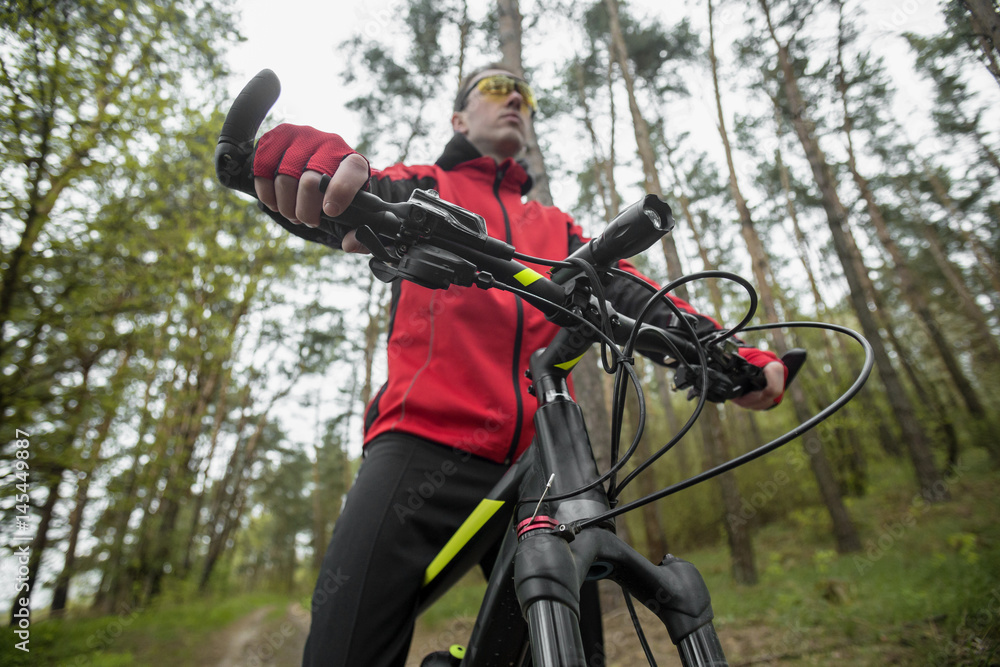 Young attractive man wears red suit ride the bike on the forest road Young attractive man wears red suit ride the bike on the forest road