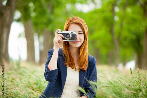 portrait of beautiful young woman holding retro camera on the wonderful park background