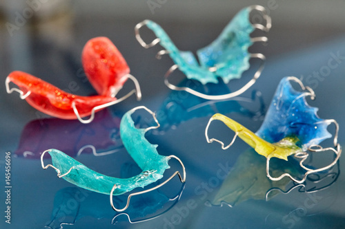 Quadro su tela Colorful dental braces or retainers for teeth on glass background