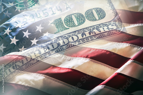 USA flag and American dollars. American flag blowing in the  wind and 100 dollars banknotes in the background.