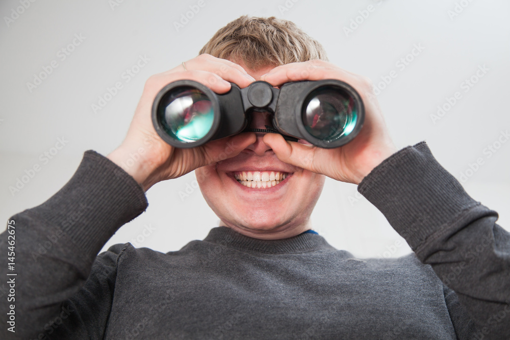 Young handsome man looking through window with binocular glasses Young handsome man looking through window with binocular glasses