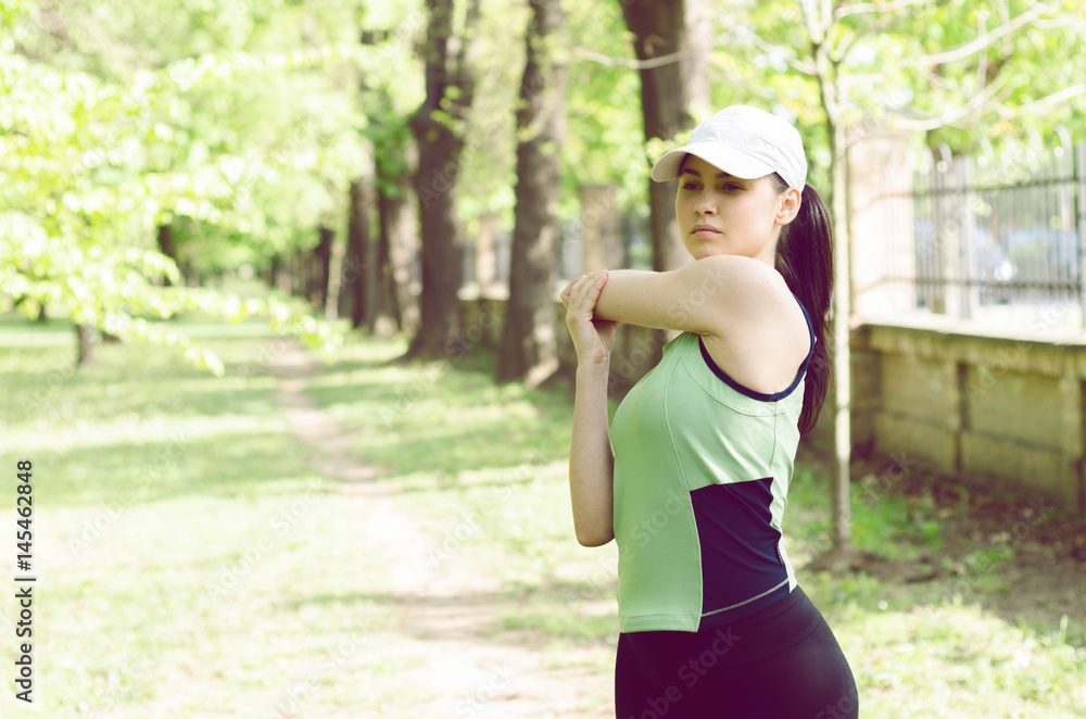 beautiful girl in sport clothes standing on the track for running and warming the muscles and ligaments beautiful girl in sport clothes standing on the track for running and warming the muscles and ligaments