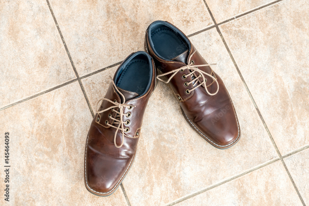Fashion brown men's shoes on a light brown ceramic tiles, view from above Fashion brown men's shoes on a light brown ceramic tiles, view from above