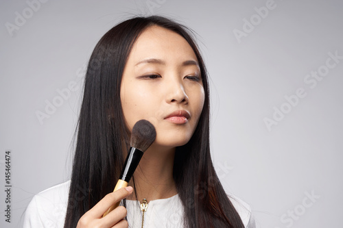 dark-haired woman holds makeup brush in her hand