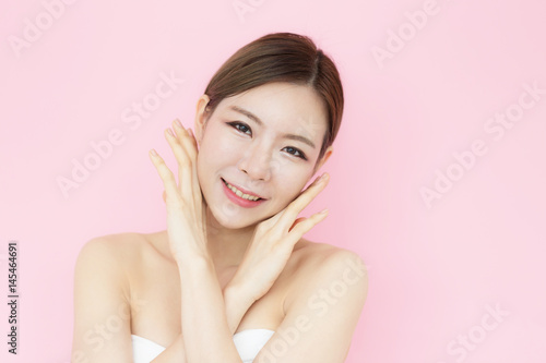 Asian beauty women stroking her face and perfect skin with copy space,isolated on pink background