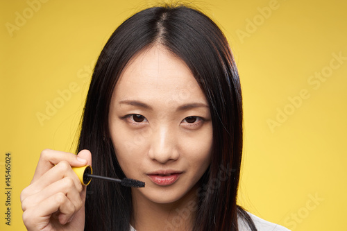 woman paints eyelashes with mascara, makeup
