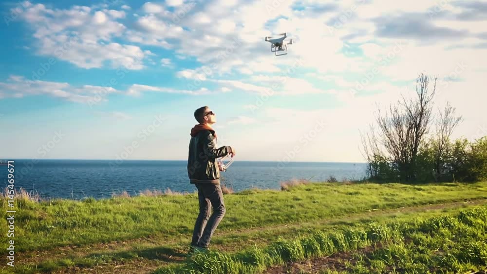 Quadrocopter drone flies over the guy and lands on the pilot's hand at sunset. The pilot catches the drone against the background of the sea and cargo ships in slow motion (90 fps). Quadrocopter drone flies over the guy and lands on the pilot's hand at sunset. The pilot catches the drone against the background of the sea and cargo ships in slow motion (90 fps).