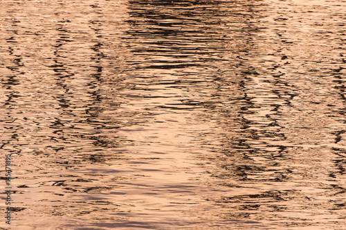 Waves on the water in pink, background. Pink shade of waves on the water surface. Ripples on the water.