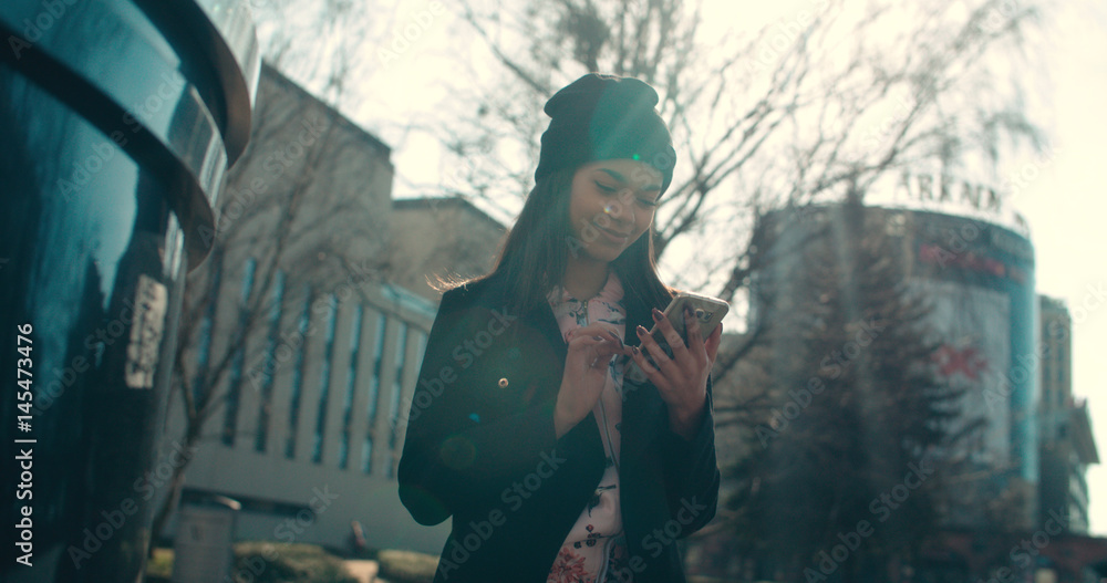 Portrait of young African American woman using phone, outdoors.
