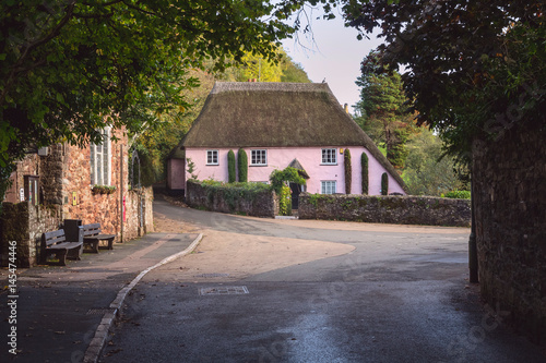 A large classic Devonian house with a thatched roof with the village of Cockington. Location near Torquay. Devon. England