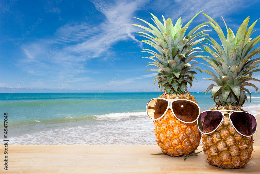 Naklejka premium pineapple with sunglasses on wood,concept summer background.