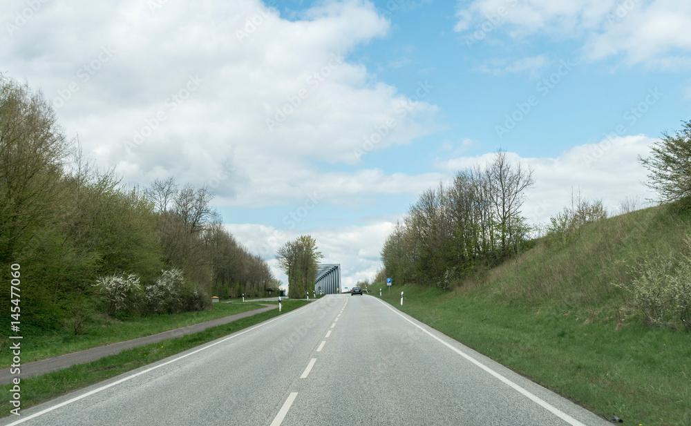 Fototapeta premium alleine auf der Strasse auf eine Brücke zu fahrend