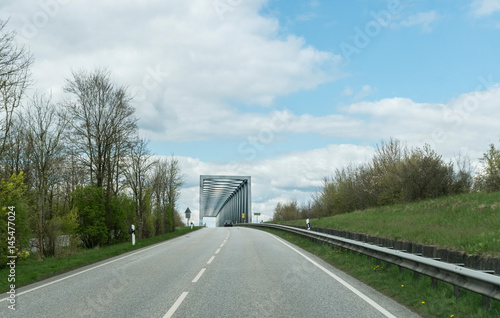 auf der landstrasse alleine auf eine alte brücke zu fahrend photo