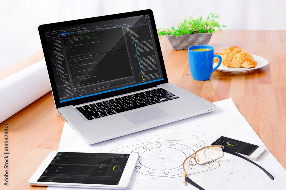Software engineer's workplace with notebook, tablet, glasses, sketching, smartphone, blue cup, croissant. Note: Program code was got from github with free license for commercial use (MIT) Software engineer's workplace with notebook, tablet, glasses, sketching, smartphone, blue cup, croissant. Note: Program code was got from github with free license for commercial use (MIT)