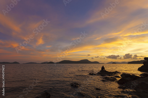 Alone man sitting on stone see beautiful sunset landscape scenery nature view in phuket thailand.