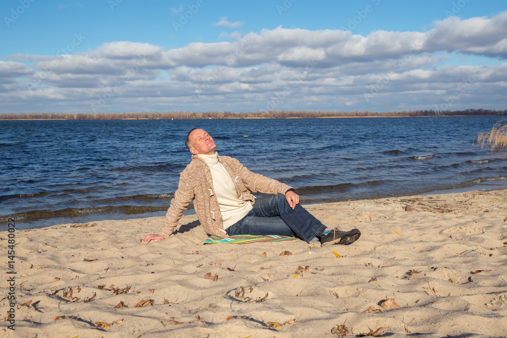 Man is sitting on the river bank and enjoying life