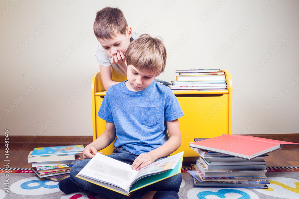 Kids reading a book. Boy reads a story to his brother at home Kids reading a book. Boy reads a story to his brother at home