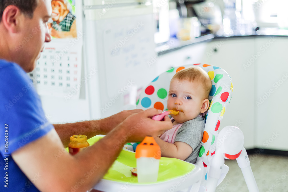 Young caring father feeding cute baby daughte at home. Family concept, soft selective focus Young caring father feeding cute baby daughte at home. Family concept, soft selective focus