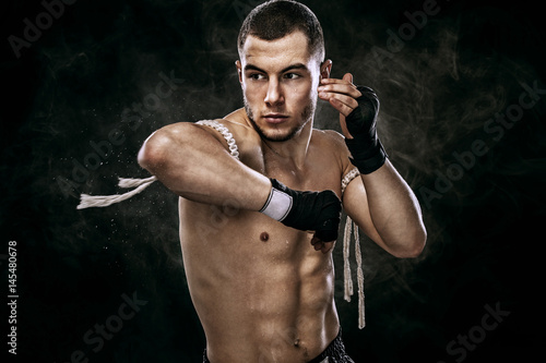 Sportsman muay thai boxer fighting in boxing cage. Background with lights and smoke. Copy Space. photo