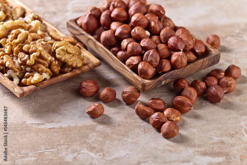 Fototapeta premium Hazelnuts and walnuts in old wooden dish