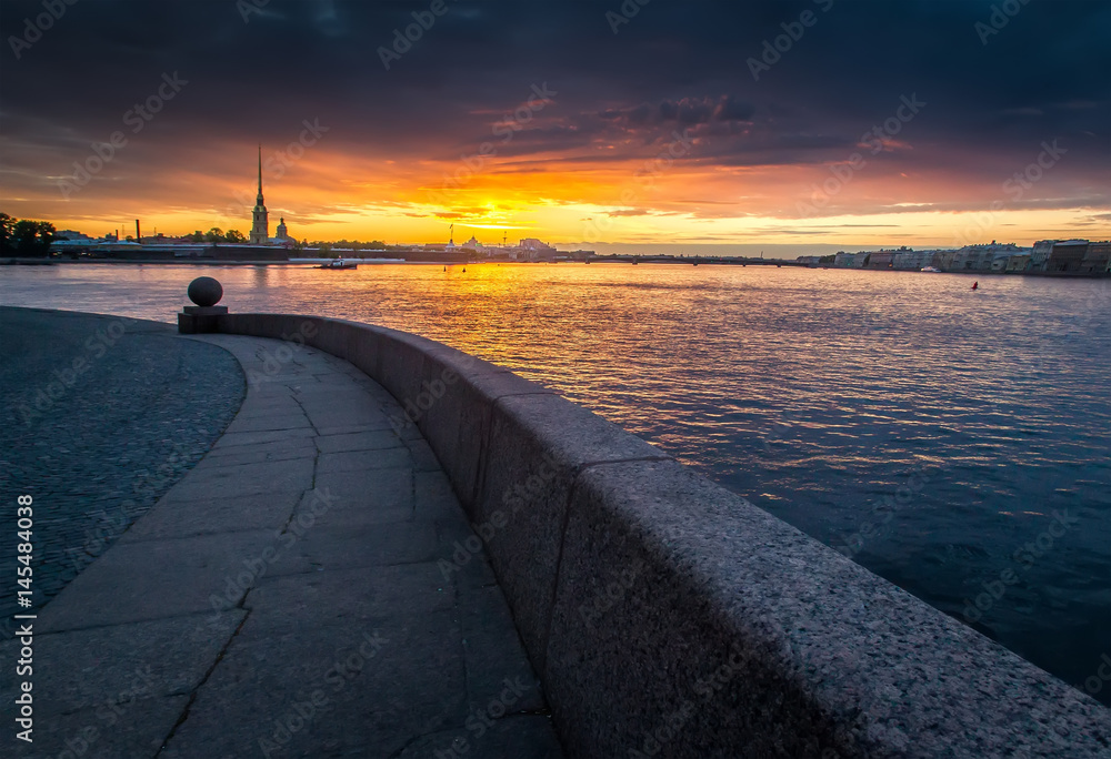 A view of the Peter and Paul Fortress and a granite ball on the Spit of Vasilyevsky Island during a colorful sunset. St. Petersburg. Russia