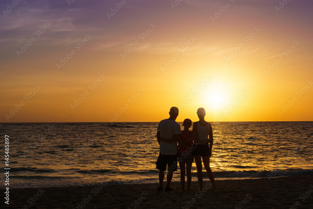 Happy family standing on the beach at the sunset time. Parents. Concept of happy family.