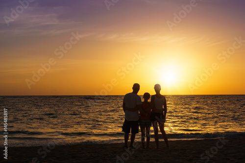 Happy family standing on the beach at the sunset time. Parents. Concept of happy family.